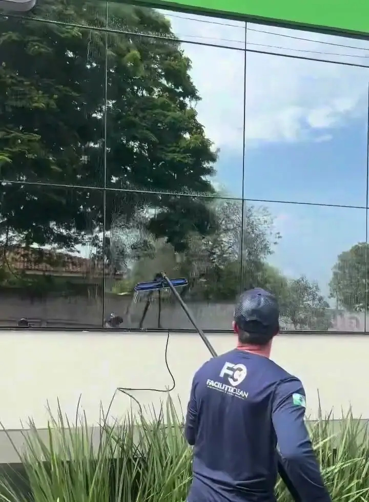 Profissional limpando vidro alto de agência com haste telescópica